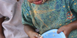 little kid with food on her face and fingers
