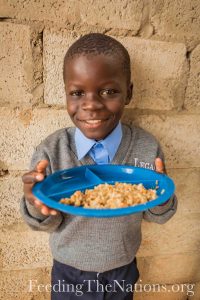 Little boy smiling with plate full of rice and beans