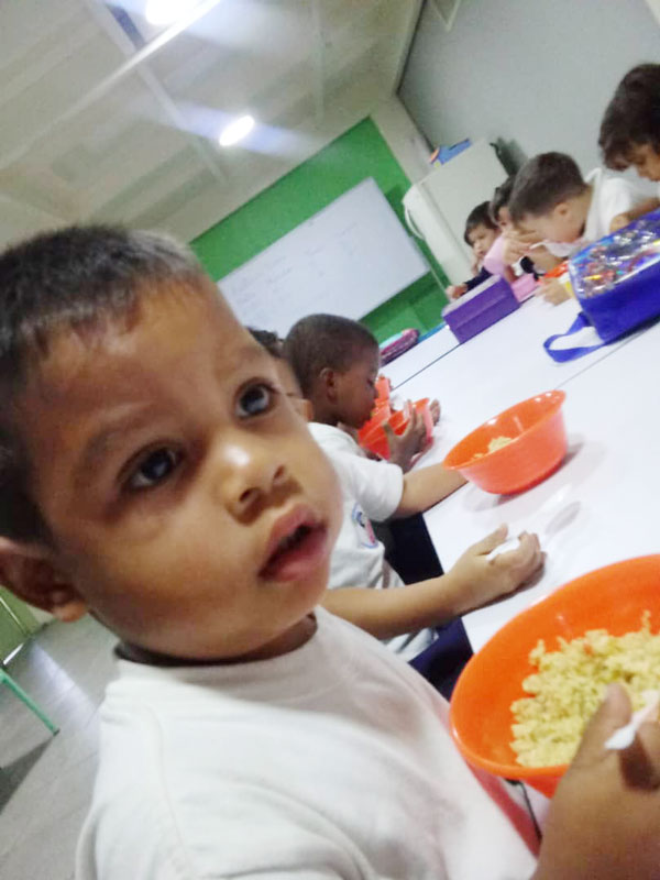 little boy and classmates with beans and rice